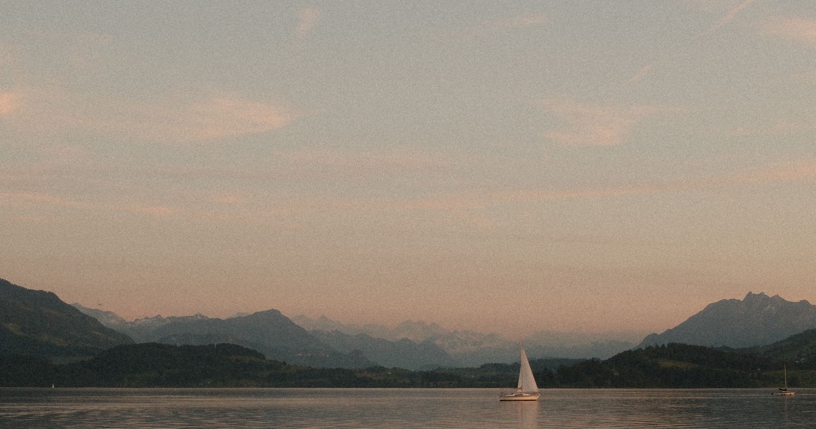 Sailboat on Lake Zug at sunset with mountains in the background, Switzerland
